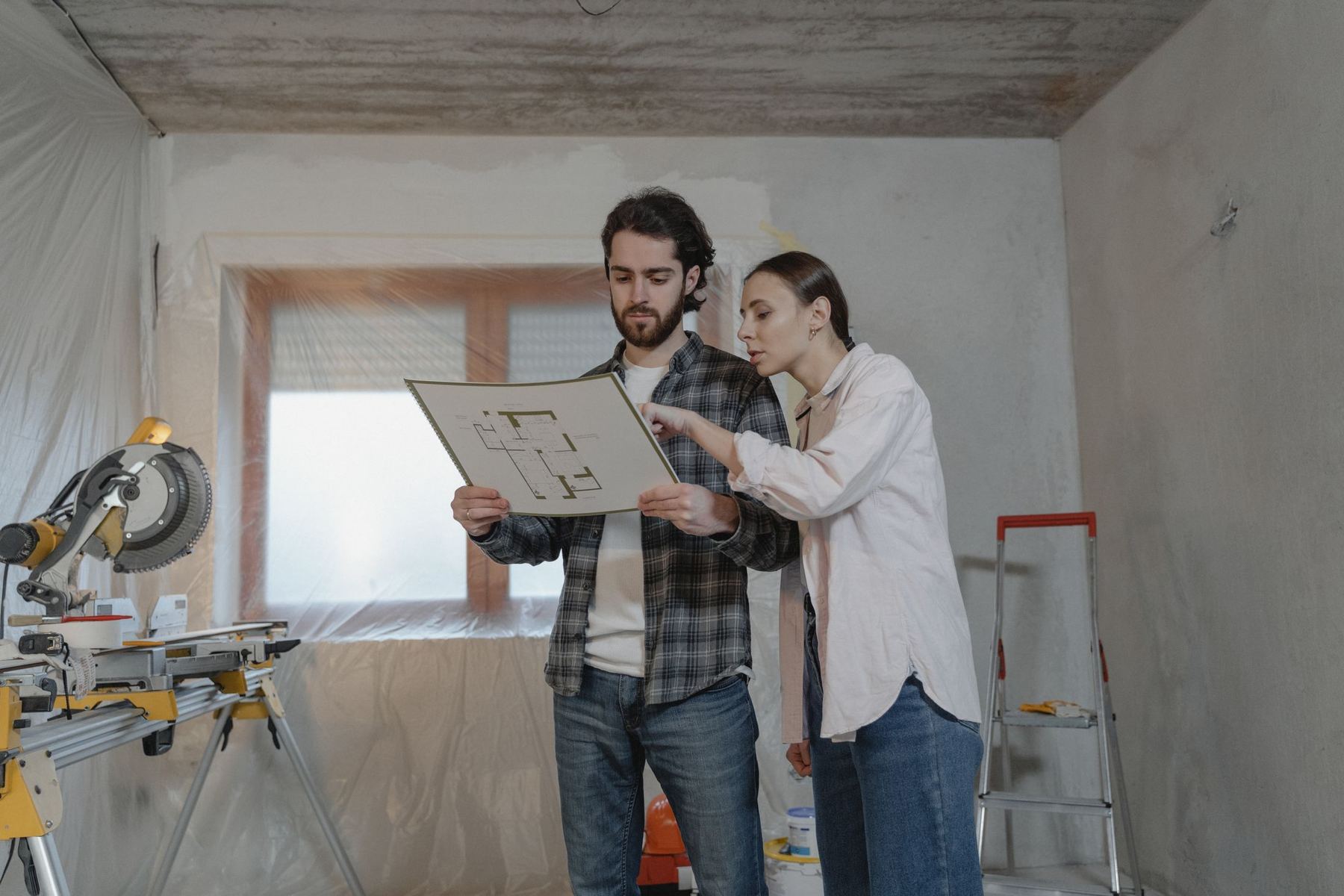 Two people reviewing drawings in a room stripped back for building work